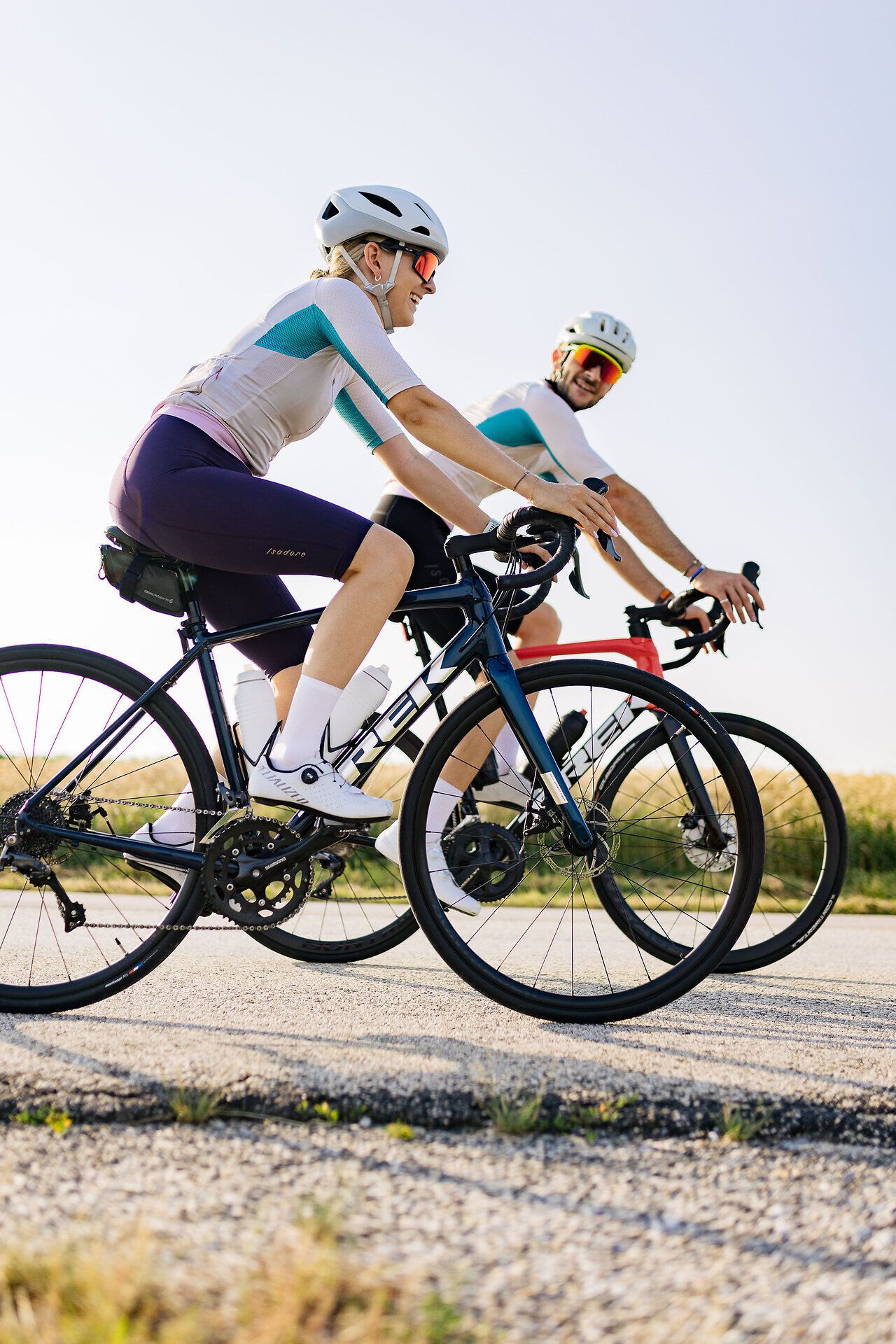 Zwei Rennradfahrer auf ihrem Bike auf der Straße lächeln in die Kamera.