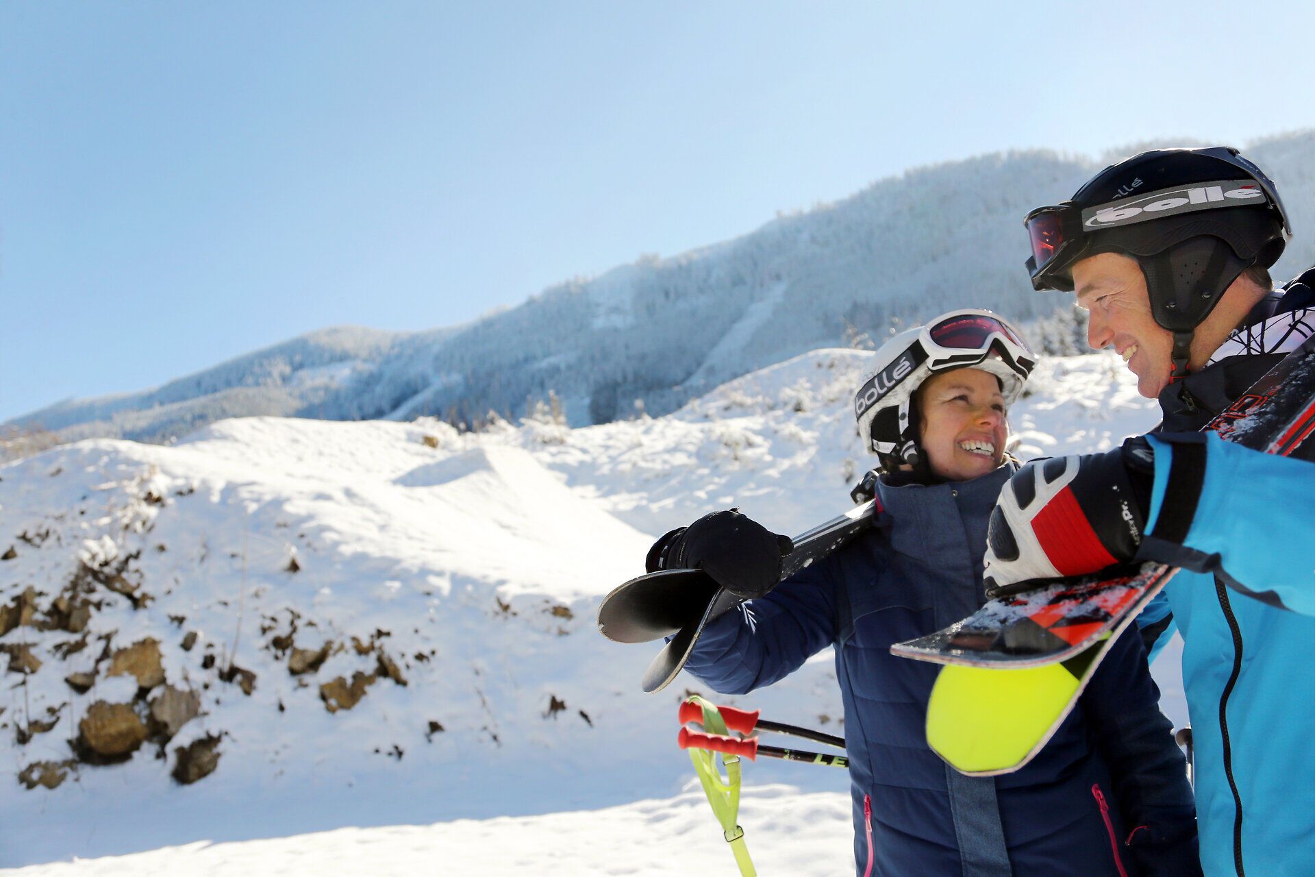 Ein strahlend blauer Himmel umrahmt die fröhlichen Gesichter einer Familie, die sich auf den Skitag vorbereitet. Umgeben von schneebedeckten Bergen und der frischen Bergluft, spüren sie die Vorfreude auf unvergessliche Abfahrten und gemeinsame Erlebnisse. Die winterliche Landschaft lädt dazu ein, die Natur in vollen Zügen zu genießen.