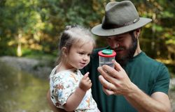 Mann zeigt einem Kleinkind eine Becherlupe in einem Wald im Naturpark NÖ Eisenwurzen. 