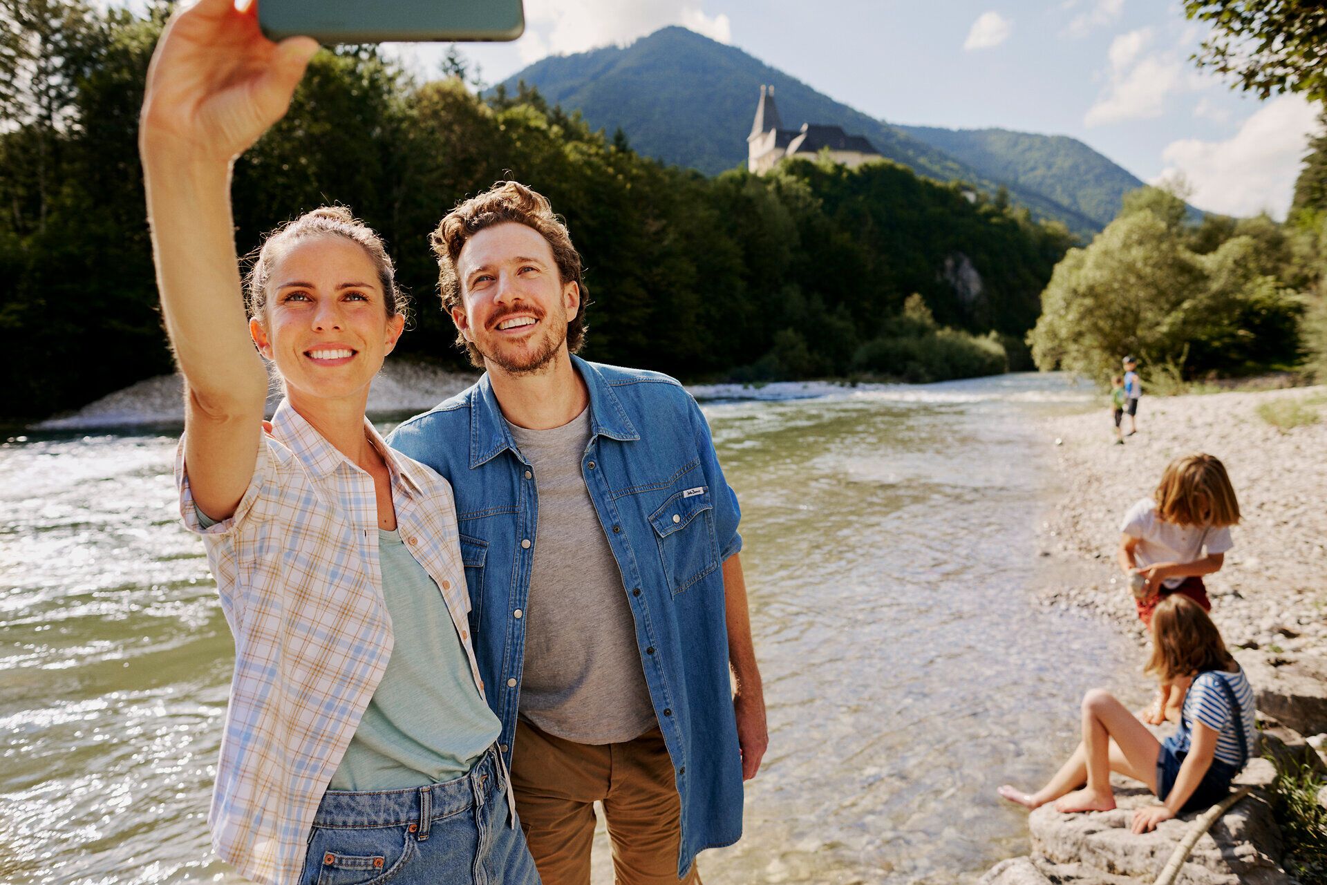 An einem sonnigen Tag genießen Familien das erfrischende Flussbaden, während Kinder fröhlich im Wasser spielen. Die malerische Kulisse der umliegenden Natur schafft eine einladende Atmosphäre für unvergessliche Momente. Hier wird der Sommer in vollen Zügen ausgelebt.