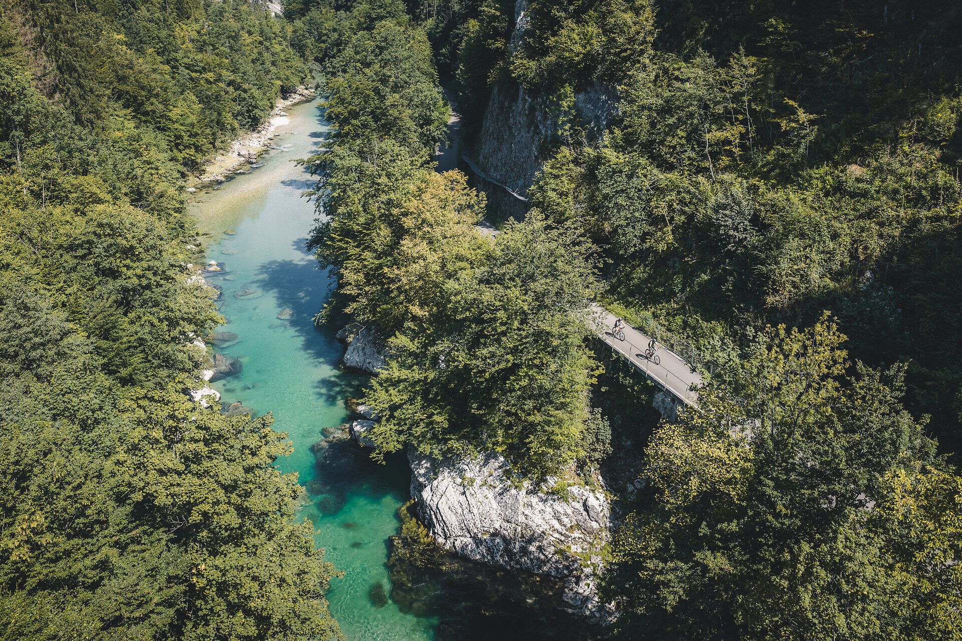 Aerial view of the Ybbs, surrounded by wooded vegetation and next to it two cyclists on the Ybbstal cycle path