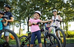 Eine fröhliche Familie genießt einen sonnigen Tag beim Radfahren in der Natur. Die Kinder strahlen vor Freude, während sie auf ihren Fahrrädern posieren, umgeben von üppigem Grün und der frischen Luft der Melker Alpenvorland. Diese harmonische Szene lädt dazu ein, die Schönheit der Landschaft und die Freude an gemeinsamen Erlebnissen zu entdecken.