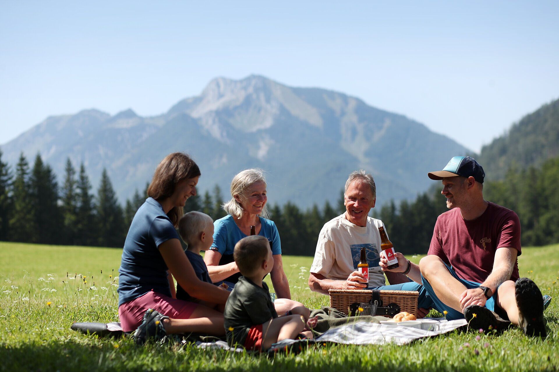 Familie macht ein Picknick auf einer Wiese im Naturpark NÖ Eisenwurzen.
