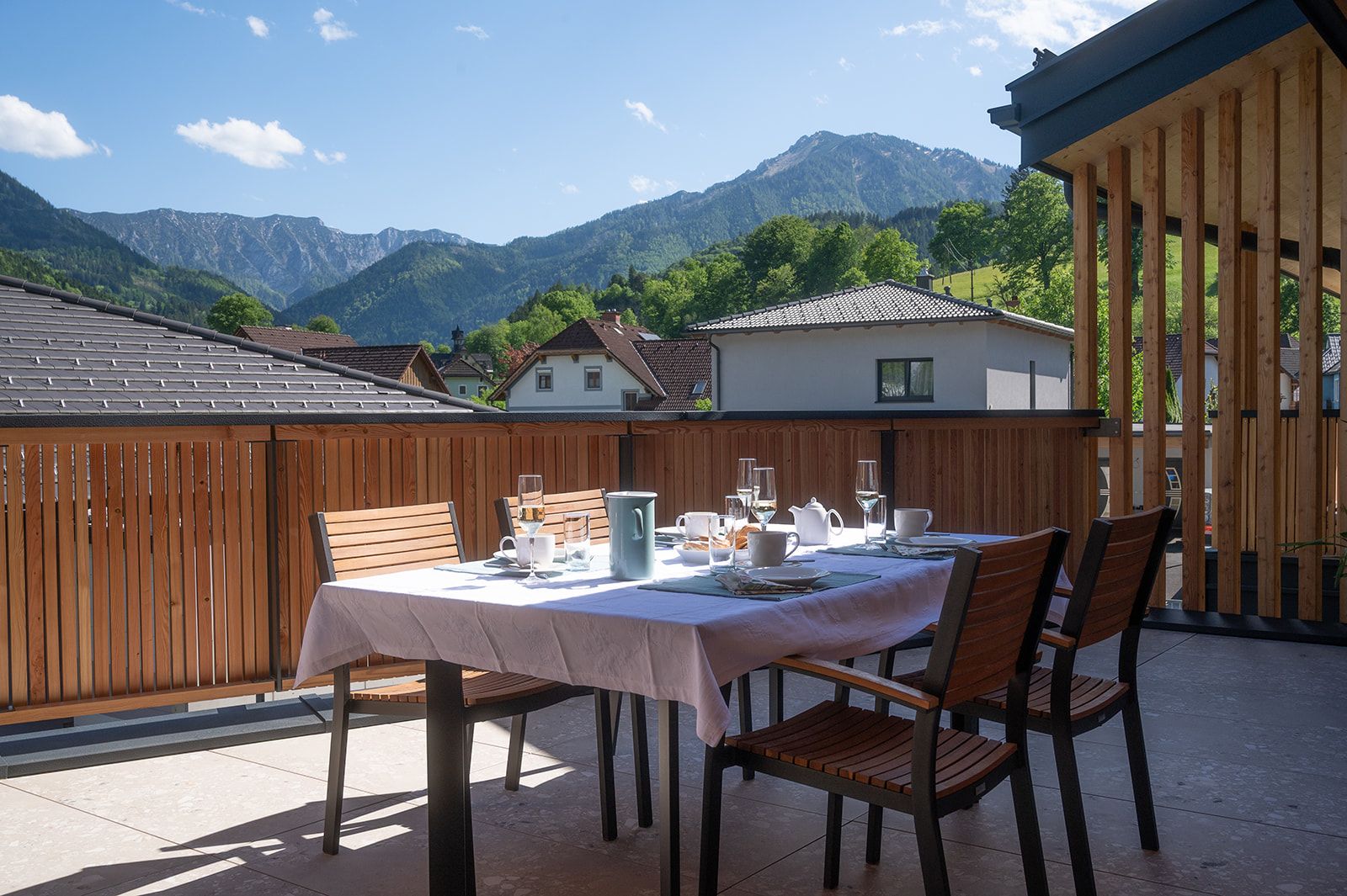 A laid table on a terrace with a view of mountains and houses.