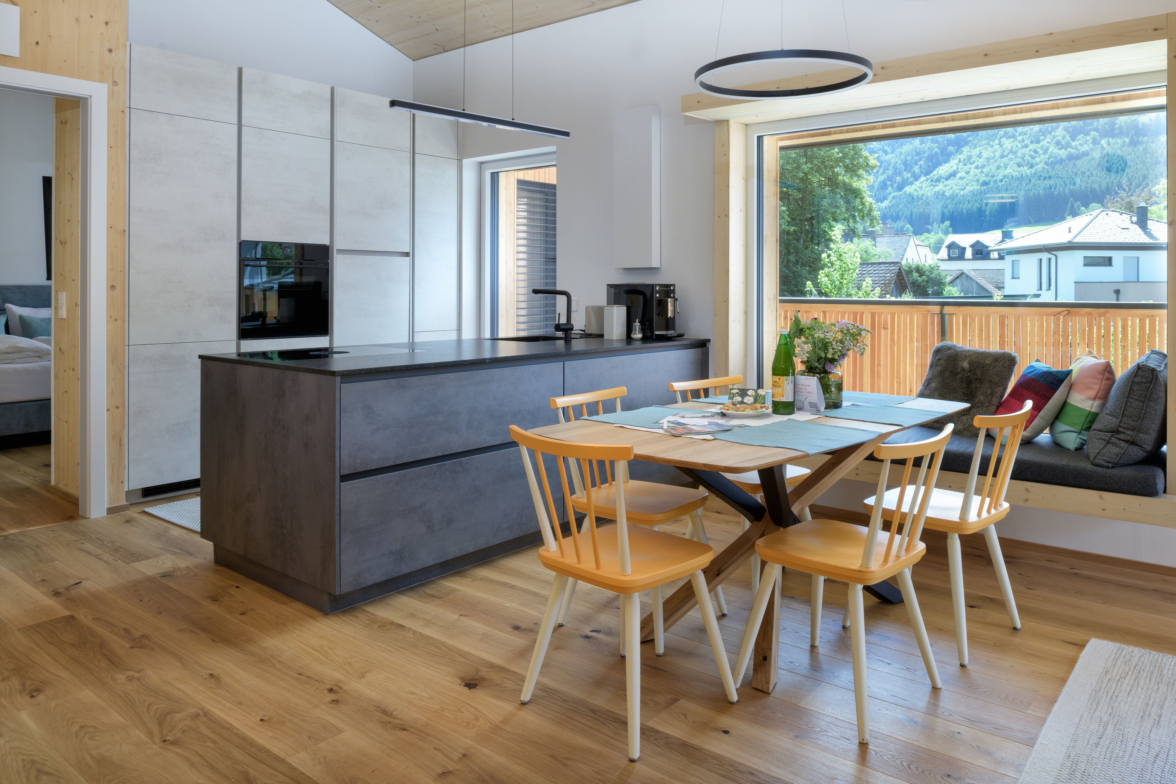 Modern kitchen with a dining table and a large window offering a view of the mountains.