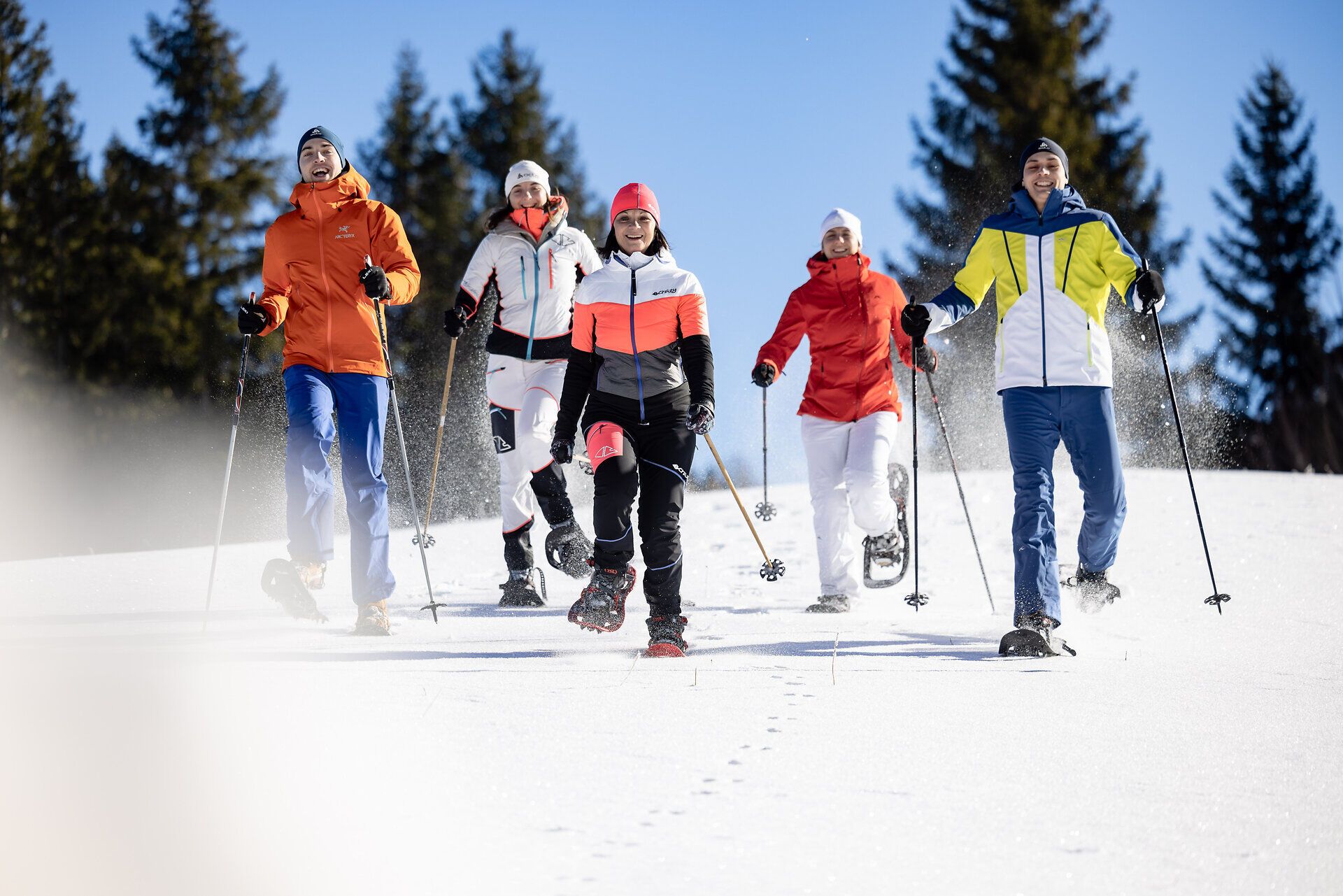 Eine Gruppe von Freunden genießt die frische Winterluft beim Schneeschuhwandern durch die verschneite Landschaft. Die strahlende Sonne und die schneebedeckten Bäume schaffen eine zauberhafte Atmosphäre, die zum Verweilen einlädt. Hier in den Bergen wird der Winter zum unvergesslichen Erlebnis.