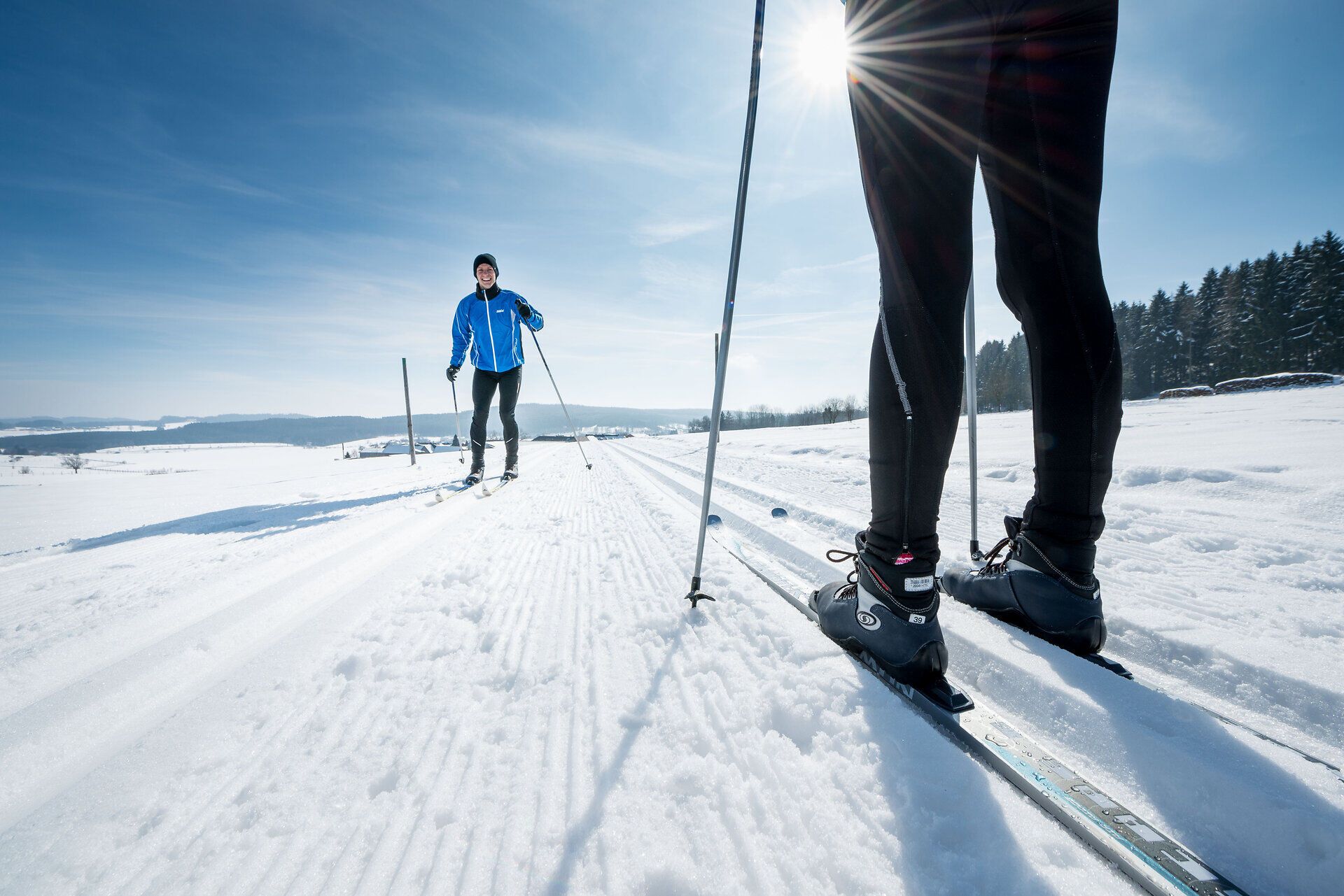 Die glitzernde Schneedecke erstreckt sich über die sanften Hügel, während die frische Winterluft die Sinne belebt. Langläufer gleiten elegant über die perfekt präparierten Loipen und genießen die Ruhe der winterlichen Landschaft. Ein unvergessliches Erlebnis für Naturliebhaber und Sportbegeisterte.