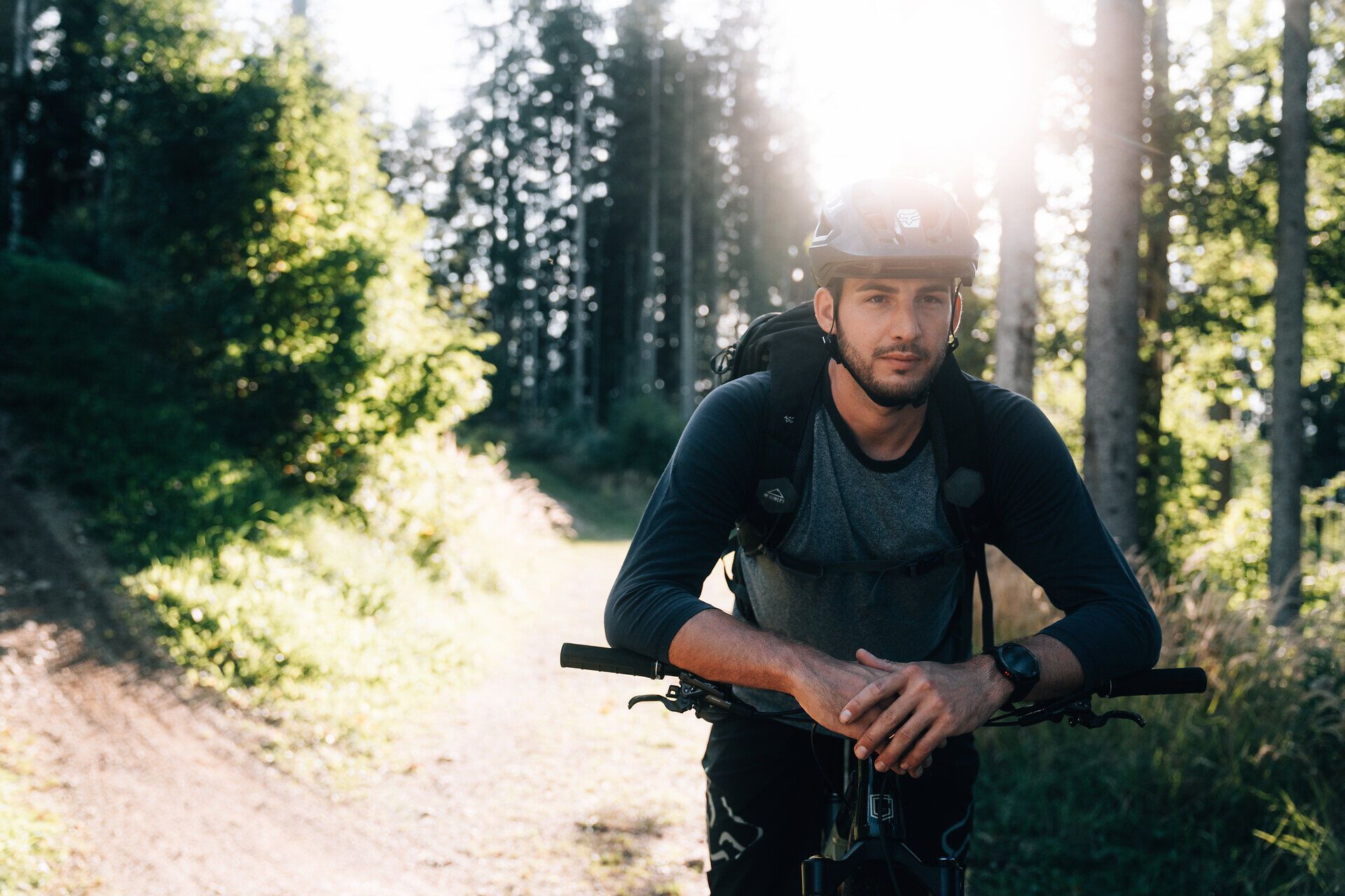 Ein Mountainbiker genießt die frische Bergluft und die atemberaubende Aussicht auf die umliegenden Wälder. Die Sonne strahlt durch die Bäume und schafft eine magische Atmosphäre, die zum Erkunden einlädt. Hier im Mostviertel wird jeder Ausflug zu einem unvergesslichen Erlebnis.