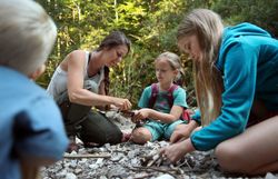 Kinder basteln unter Anleitung einer Naturvermittlerin mit Naturmaterialien im Wald im Naturpark NÖ Eisenwurzen im Mostviertel.